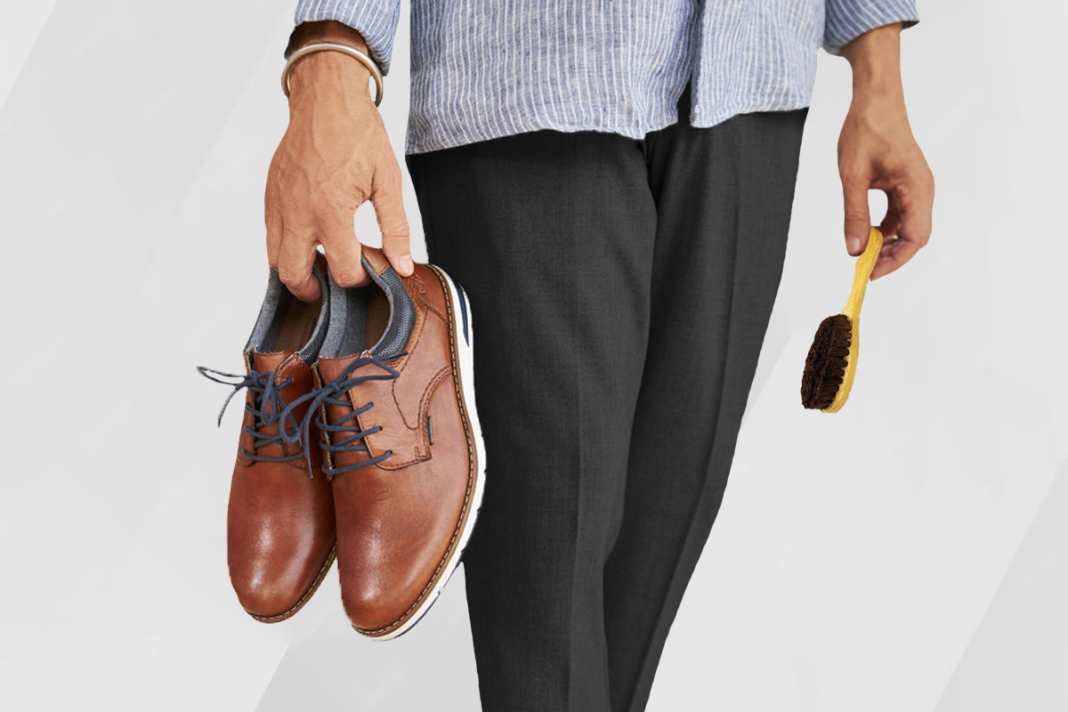 guy holding brown shoes and shoe brush